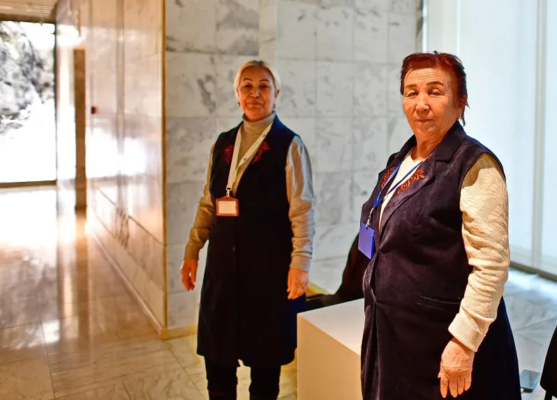 Lächelnde Frauen putzen Bettwäsche in einem Hotelzimmer