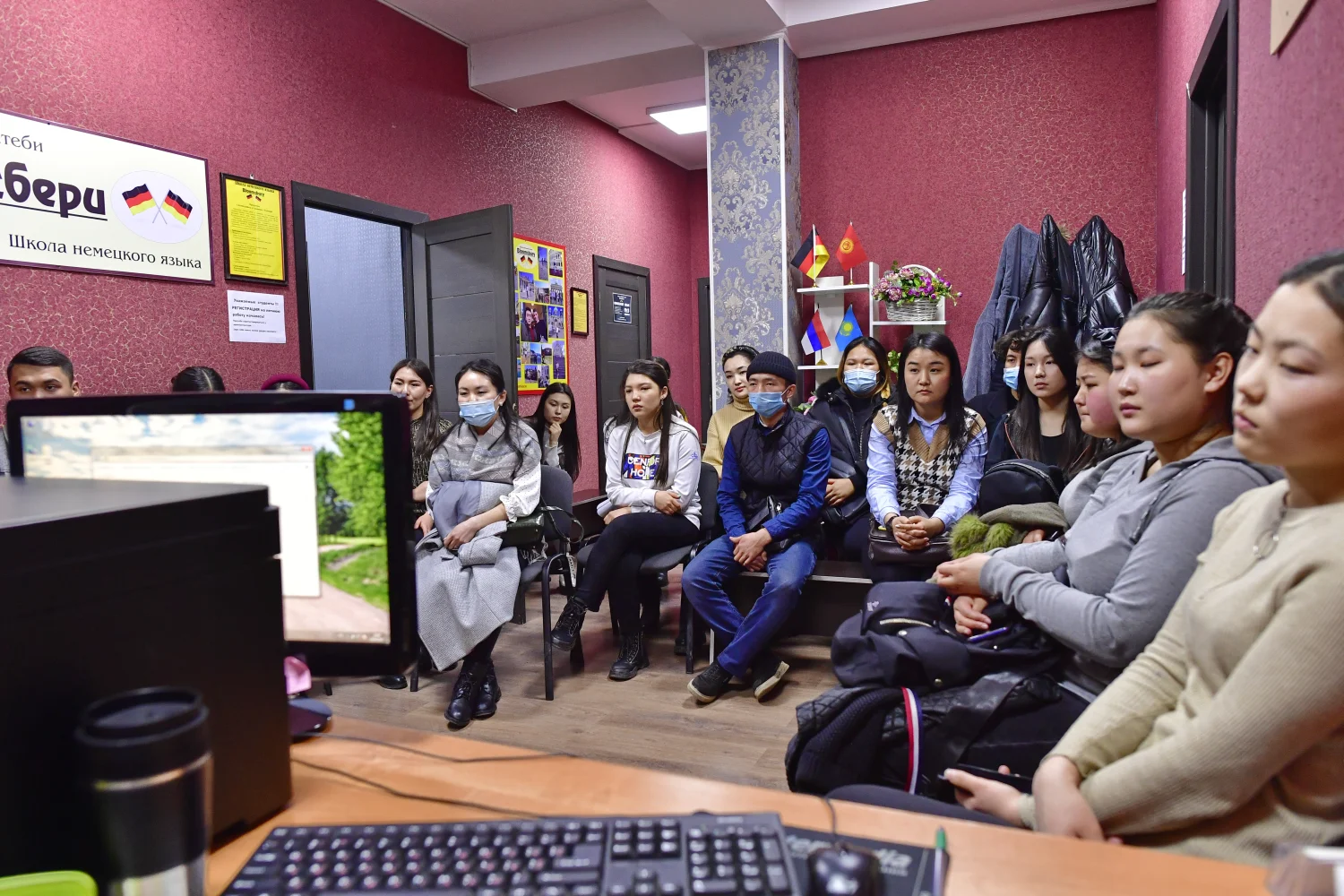 Schüler sitzen in einem Raum und schauen sich etwas auf einem Computerbildschirm an
