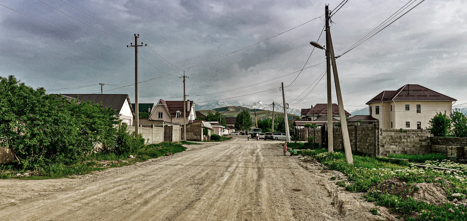 Berge, unbefestigte Straße und Häuser